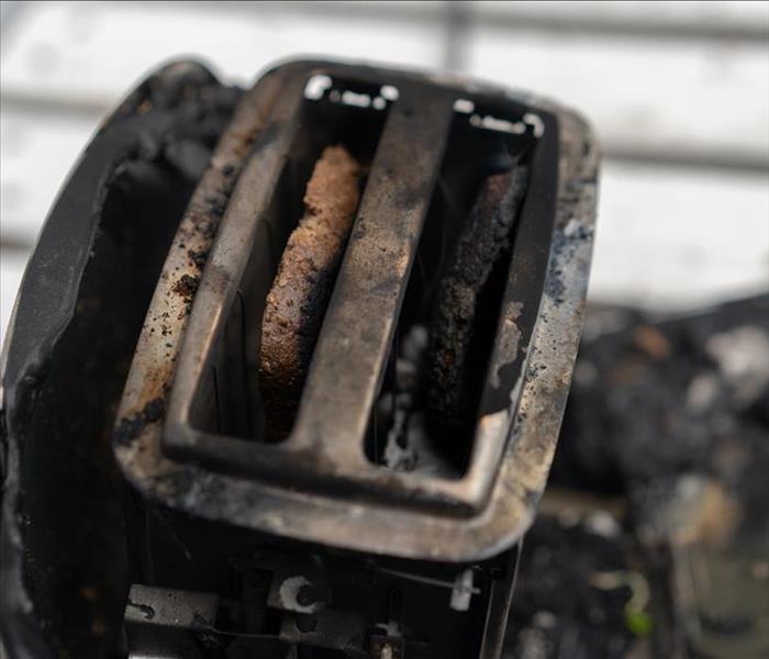A toaster with extensive fire and soot damage.